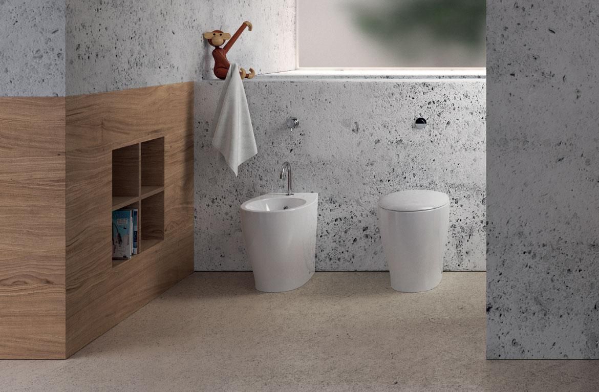 Un bagno con due WC e parete in marmo.