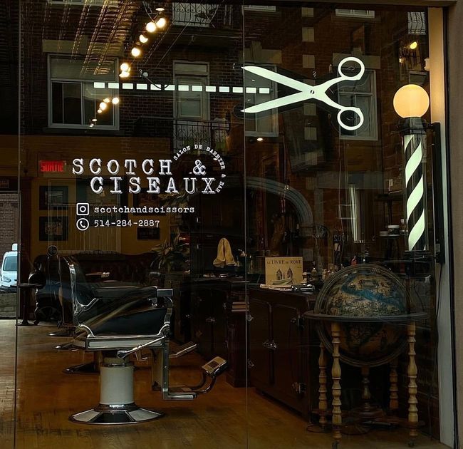 Barbershop storefront with glowing scissors sign and “Scotch Ciseaux” lettering on the window