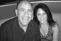 Man with glasses and woman smiling, posing together indoors.