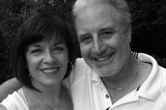 Woman with dark hair and man with gray hair smiling, close-up shot.