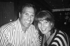 Man and woman smiling, close together. Man in striped shirt, woman in striped top. Indoor setting.