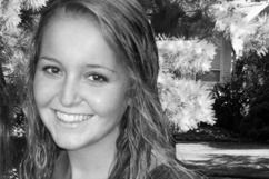 Woman with long hair smiles broadly, in front of trees. Black and white photo.