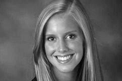 Blond woman smiling, with long hair, looking at the camera, in a studio setting.