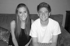 Woman and man sitting on a couch, smiling at the camera. Black and white.