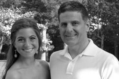 Woman and man smiling, outdoors; trees in the background.