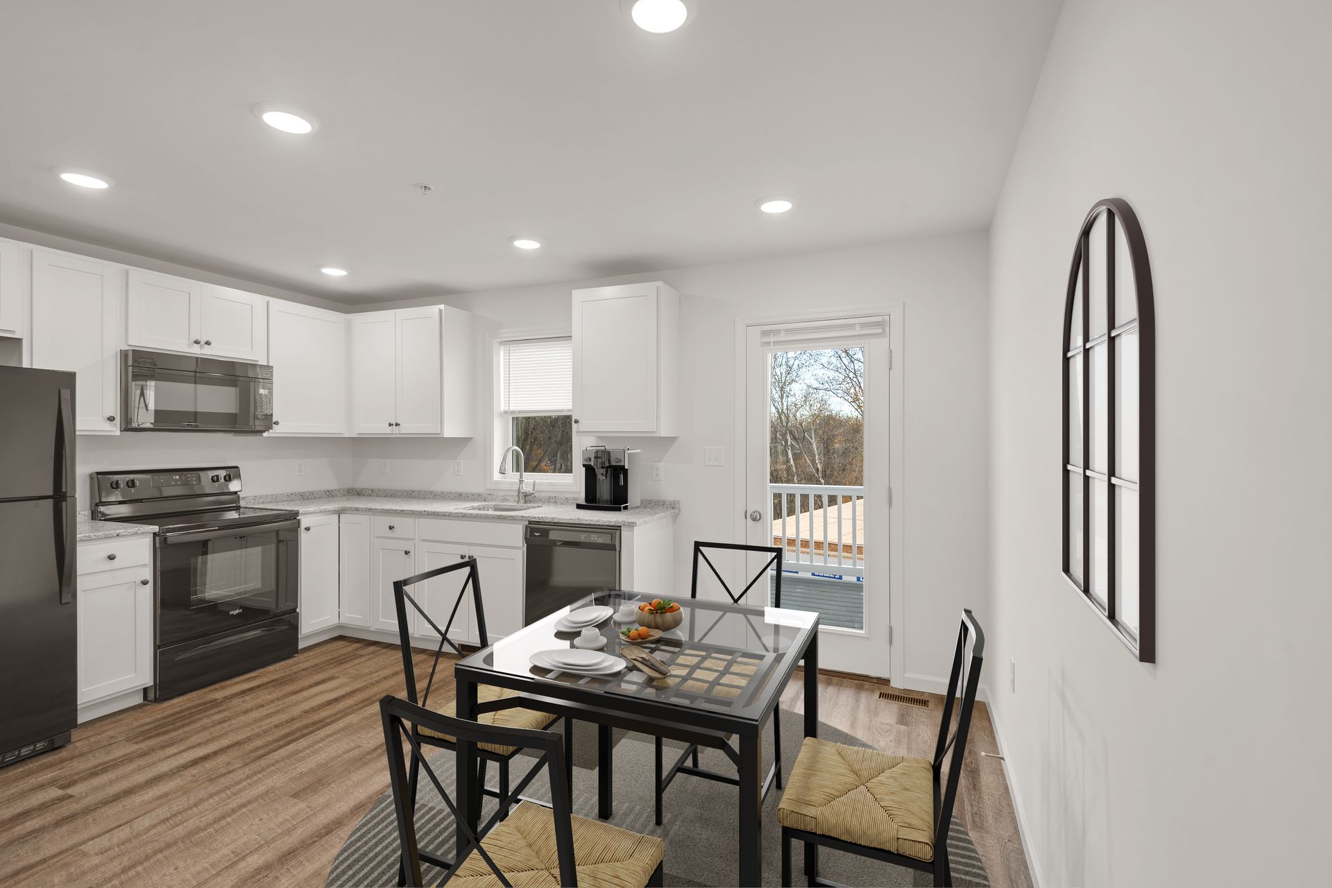 A kitchen with white cabinets , stainless steel appliances , a table and chairs.