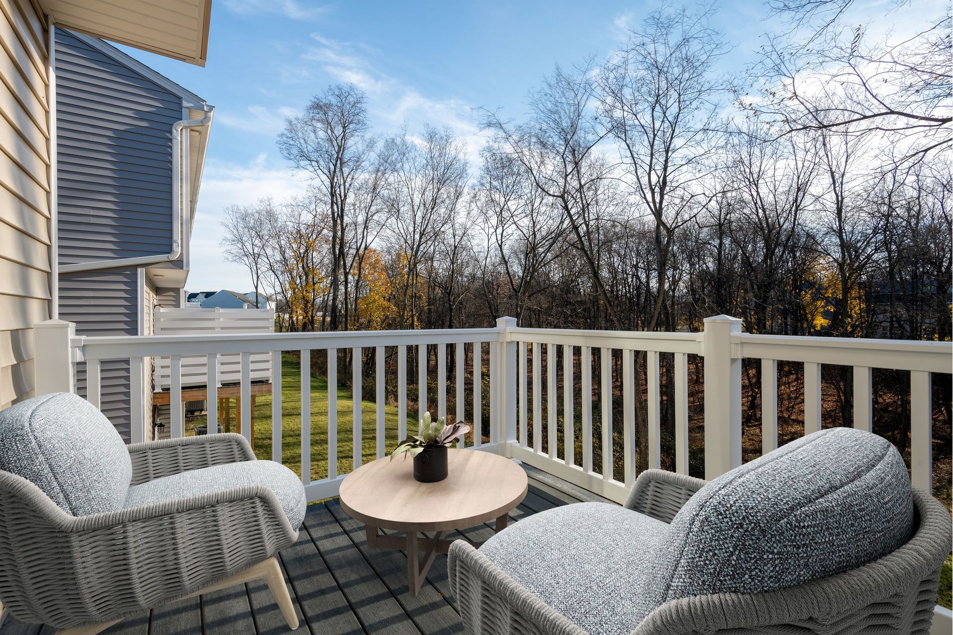 There are two chairs and a table on the balcony.
