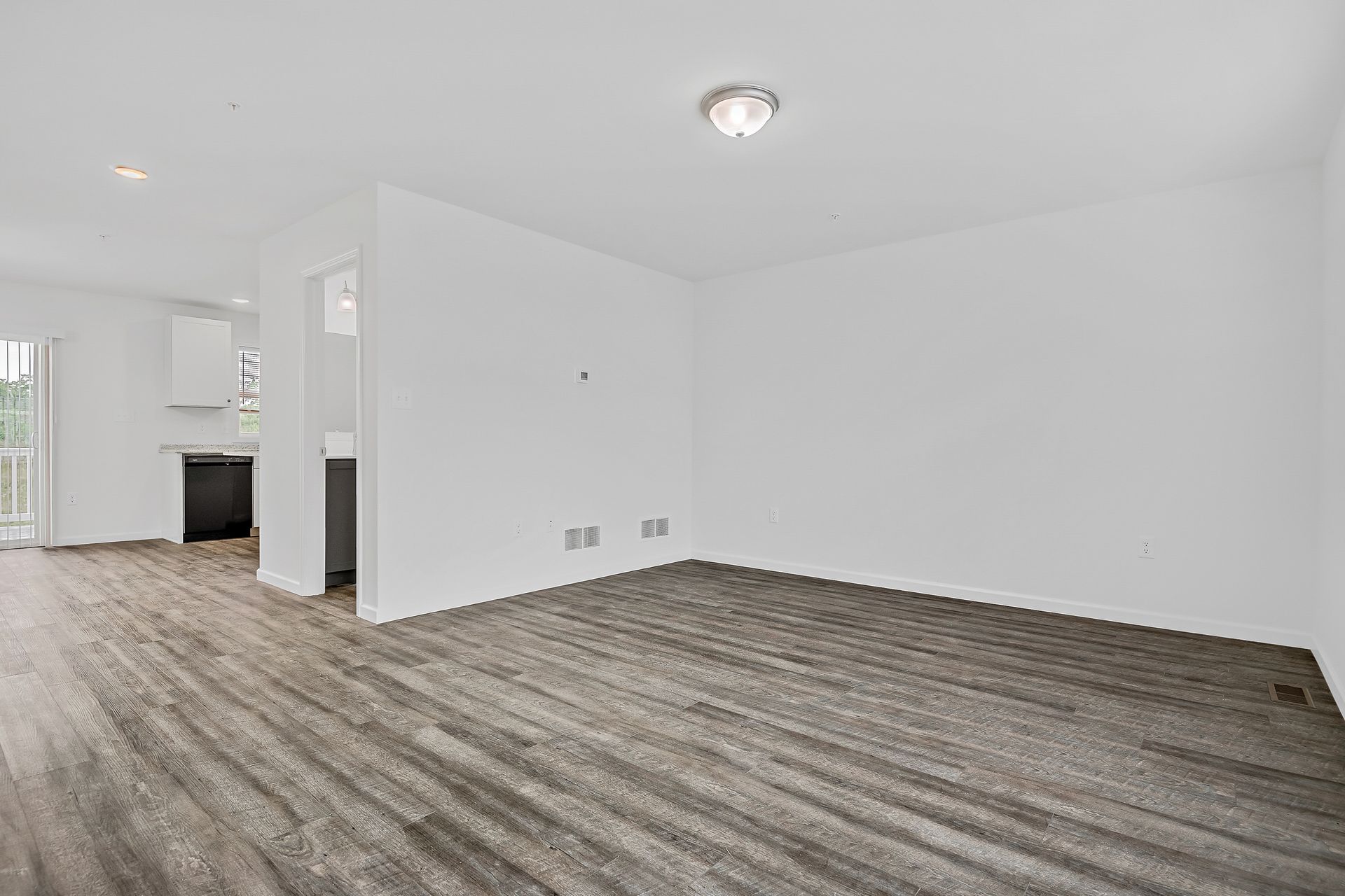 An empty living room with hardwood floors and white walls.