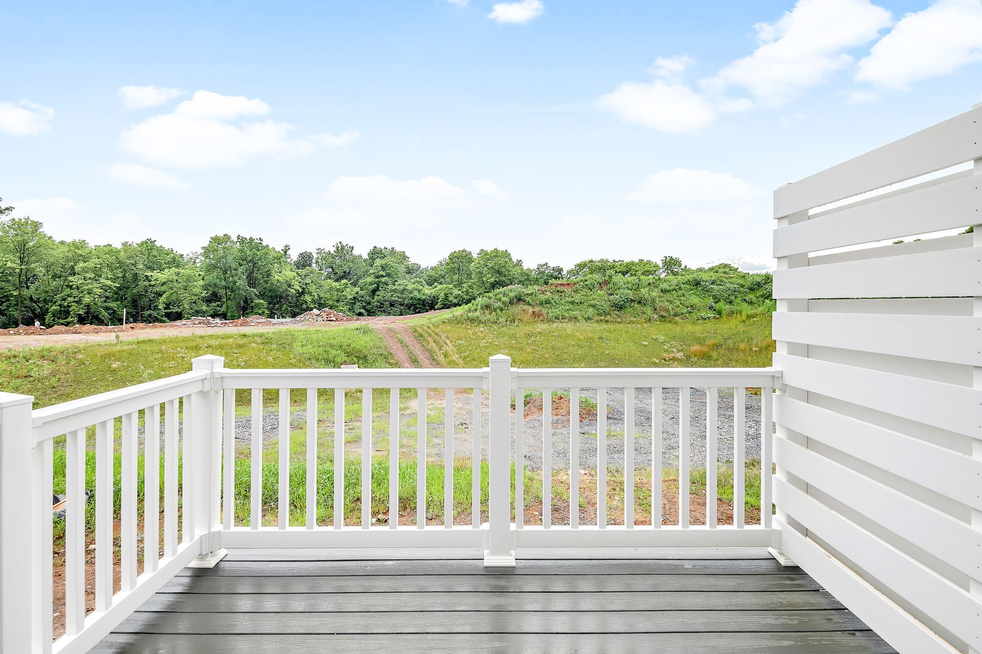 A balcony with a white railing and a view of a field.