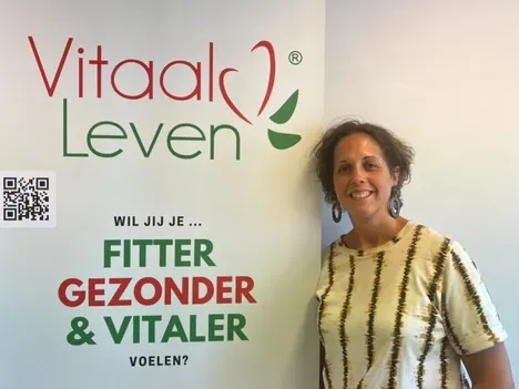 Een vrouw staat voor een muur met de tekst vitaal leven
