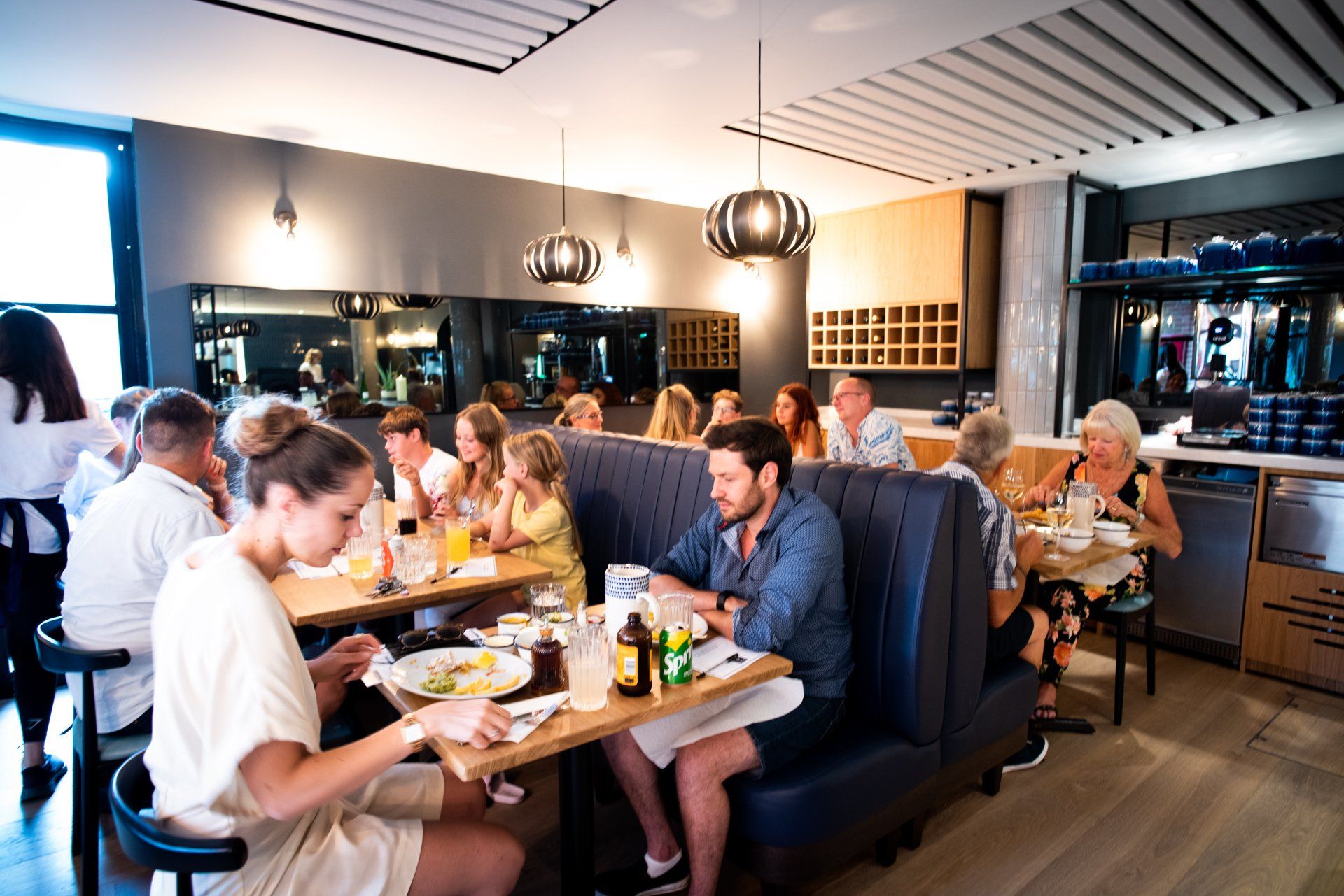 A group of people are sitting at tables in a restaurant eating food.