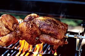A chicken is being cooked on a grill over a fire.