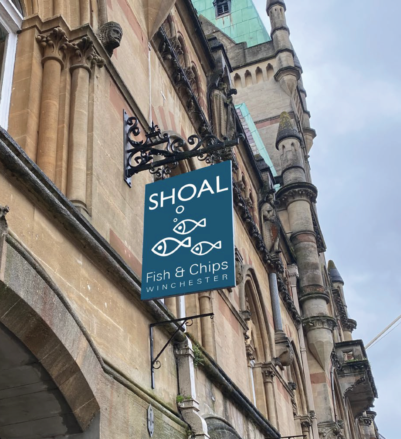 A sign for shoal fish and chips hangs on the side of a building