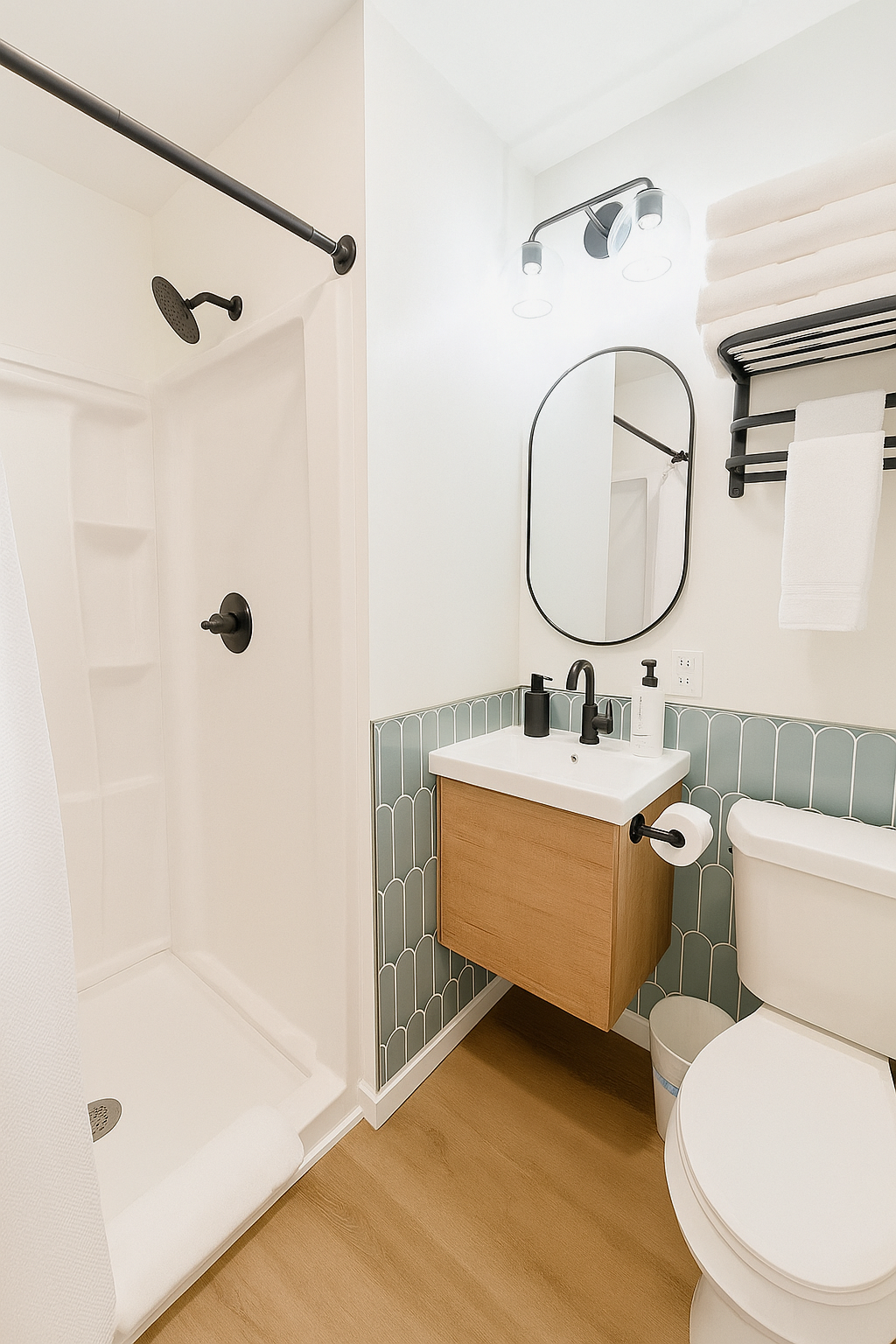 Modern bathroom with shower, vanity, and toilet. Light wood floors, white walls, teal tile accent. Black fixtures.