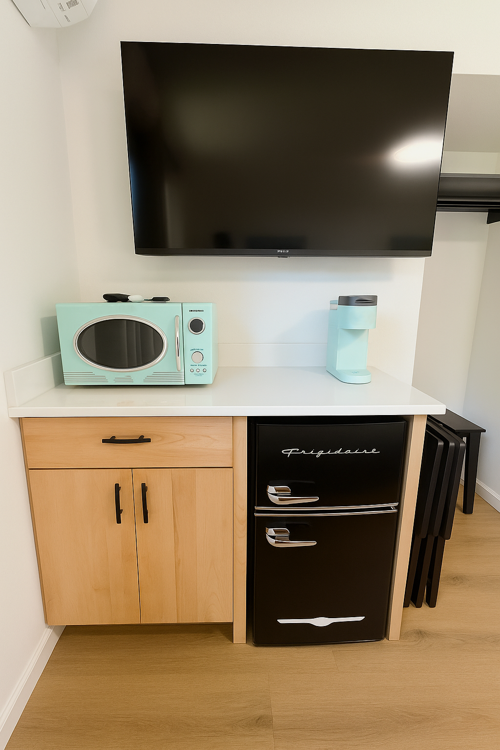 Small kitchenette with a retro-style microwave and refrigerator; a TV hangs above.