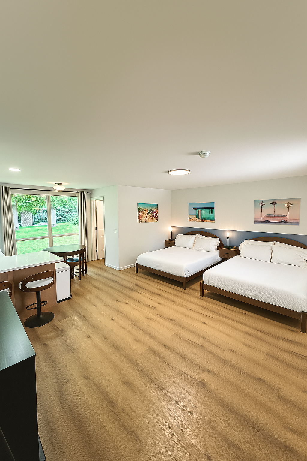Hotel room with two queen beds, a small table, and wood-look flooring.