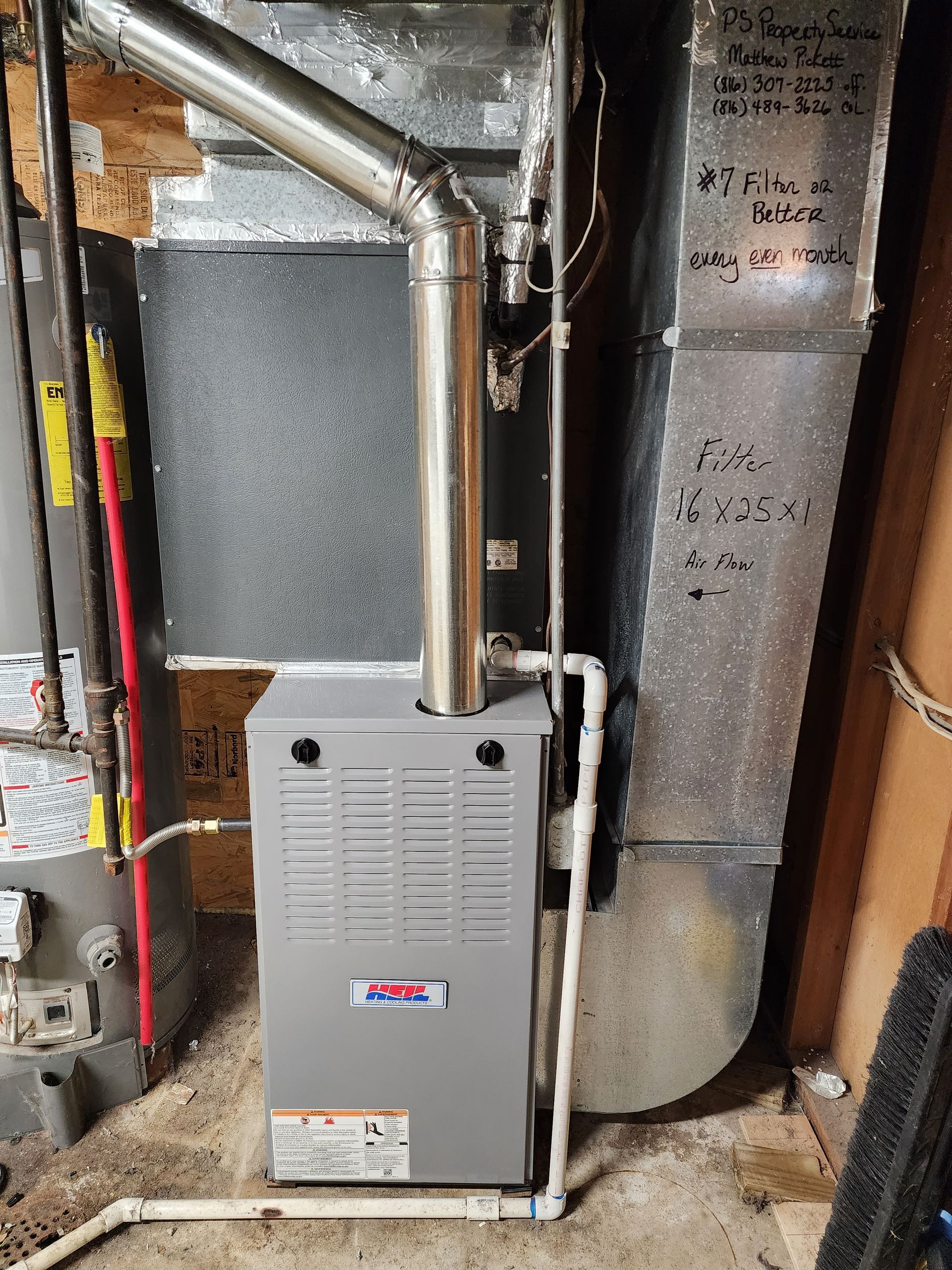 A gray HVAC furnace with a metallic exhaust pipe and white PVC piping installed next to a water heater in a basement.