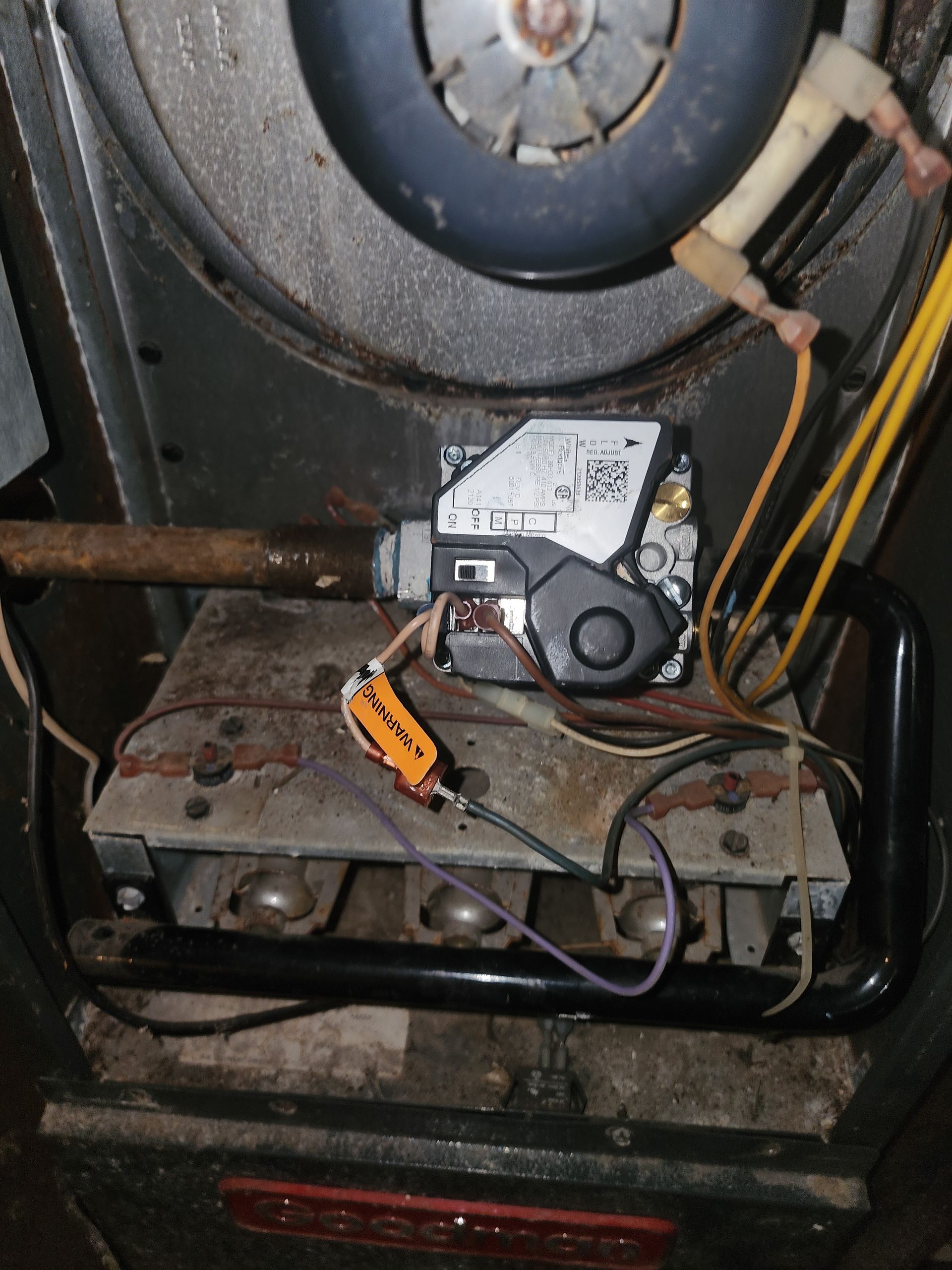 Close-up of a gas furnace interior showing the gas valve, burner assembly, wiring, and metal ventilation components.