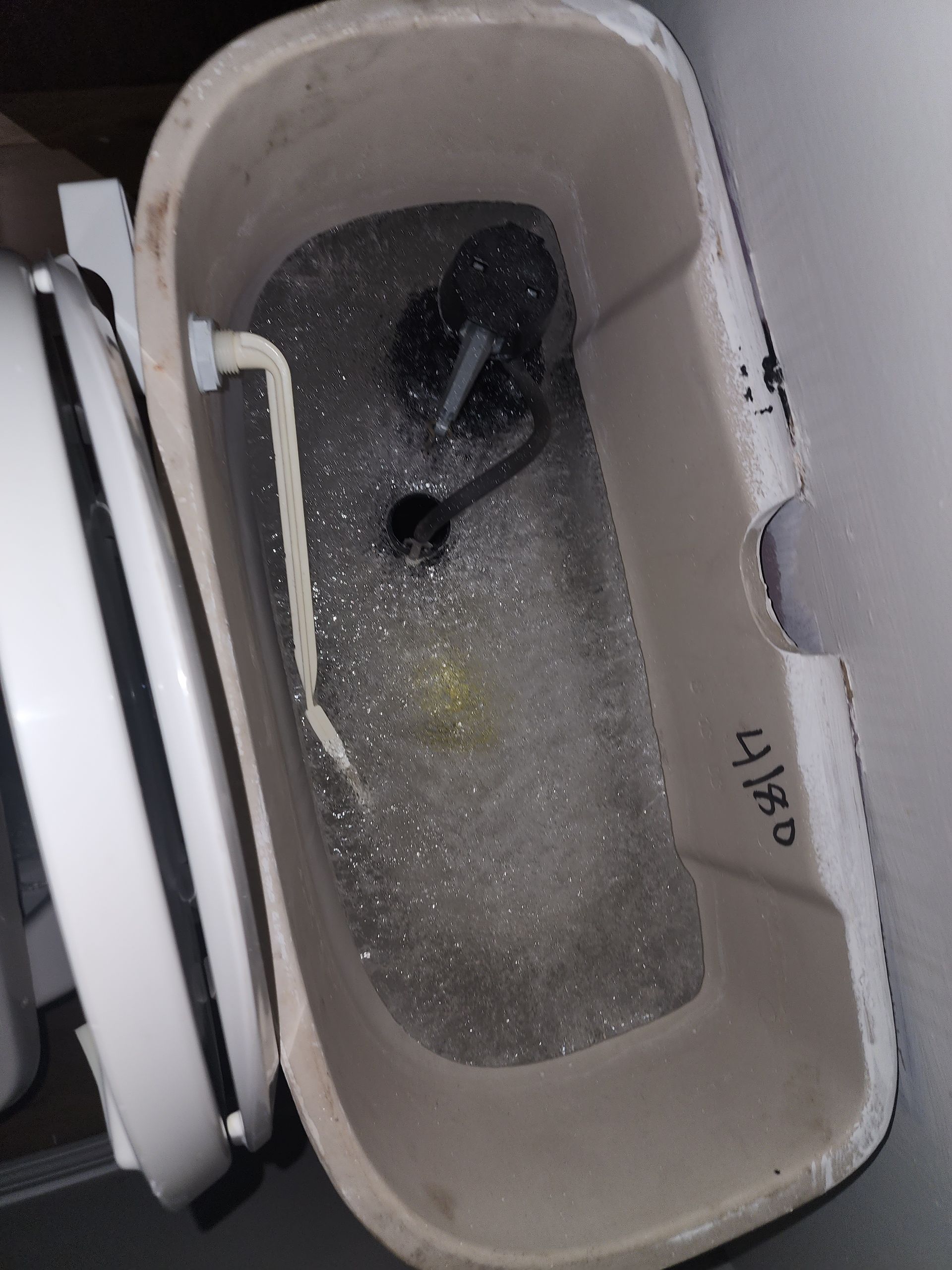 An open toilet tank showing the internal flushing mechanism and fill valve components submerged in water.