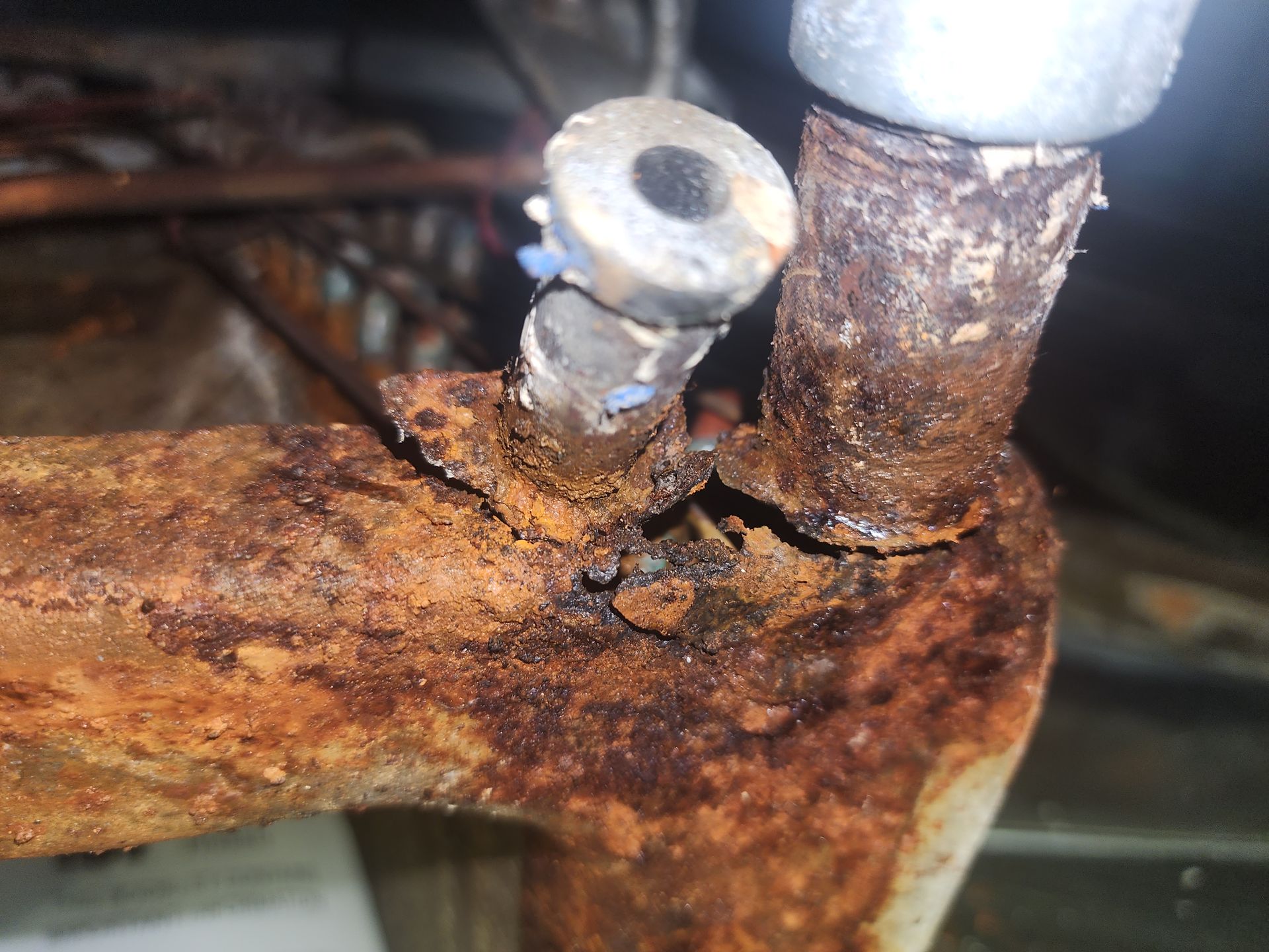 Severe rust and corrosion on metal machinery components, including two upright bolts and surrounding structural supports.