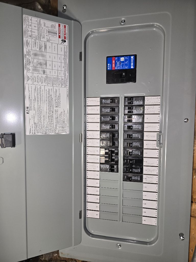 An open electrical panel with multiple circuit breakers and a white information label inside the metal door.