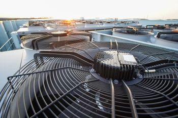 Outdoor rooftop HVAC units with large circular fans at sunset