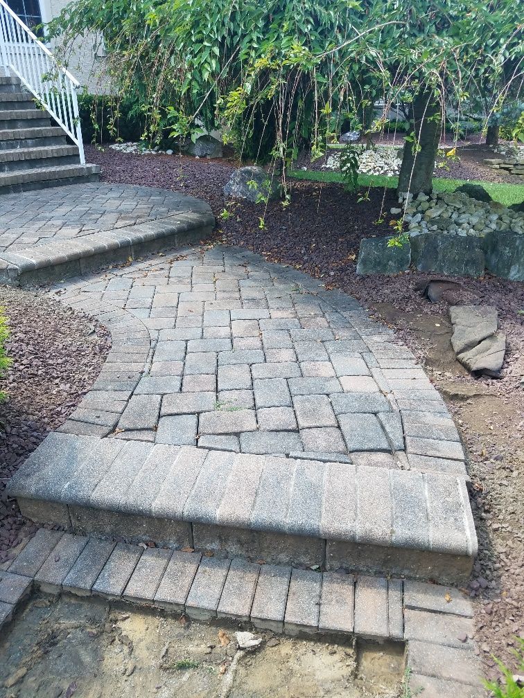 A brick walkway with stairs leading up to a house.