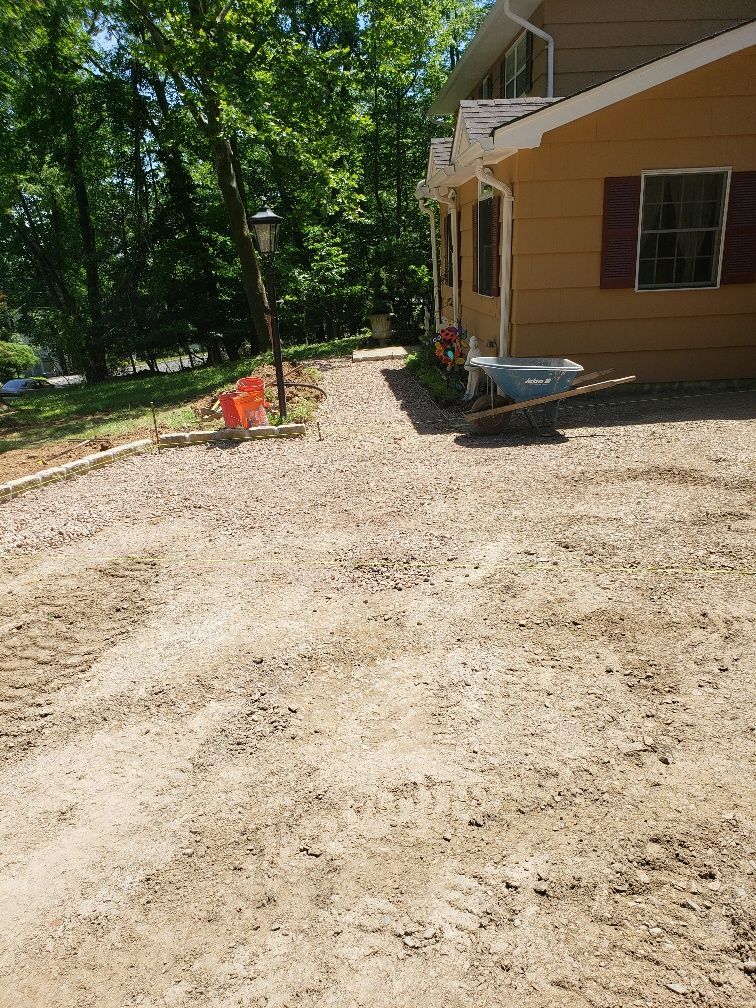 There is a wheelbarrow in the dirt in front of a house.