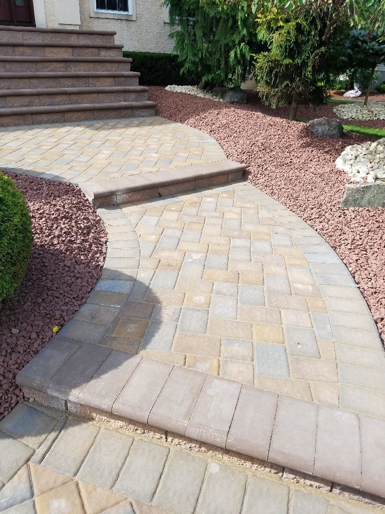 A brick walkway leading to a house with stairs.