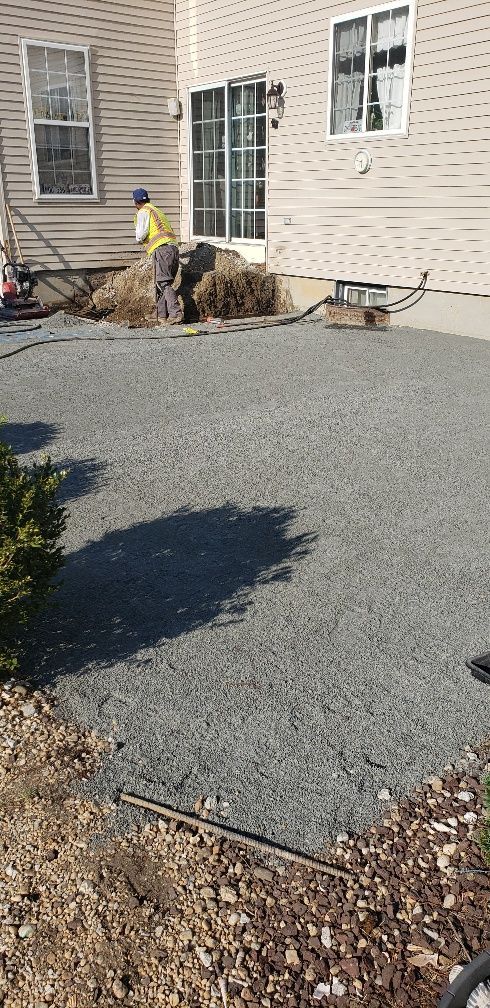 A man is working on a driveway in front of a house.