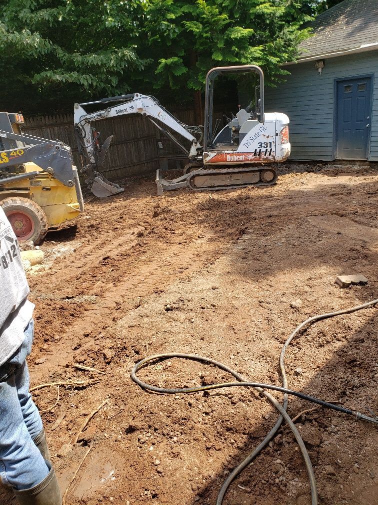 A man is standing in the dirt next to a bulldozer.