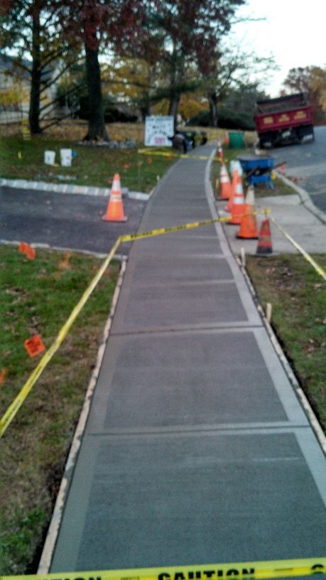 A sidewalk is being built with cones and a caution tape.