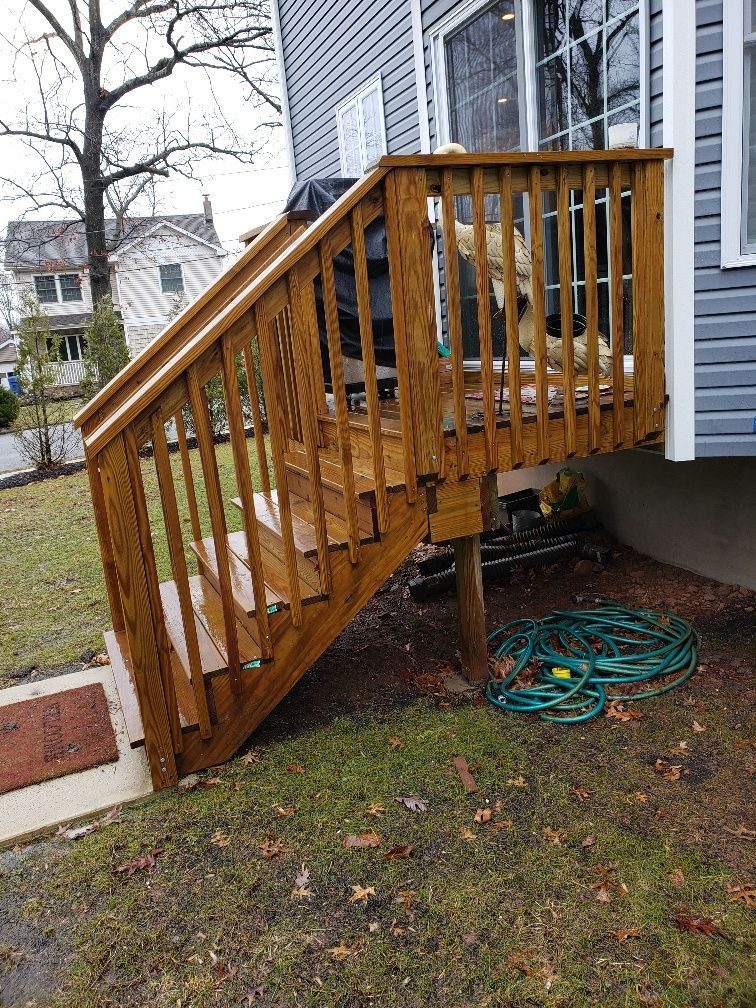 A dog is sitting on a wooden deck next to a house.