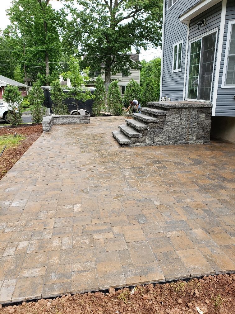 A patio with stairs and a stone wall in front of a house.