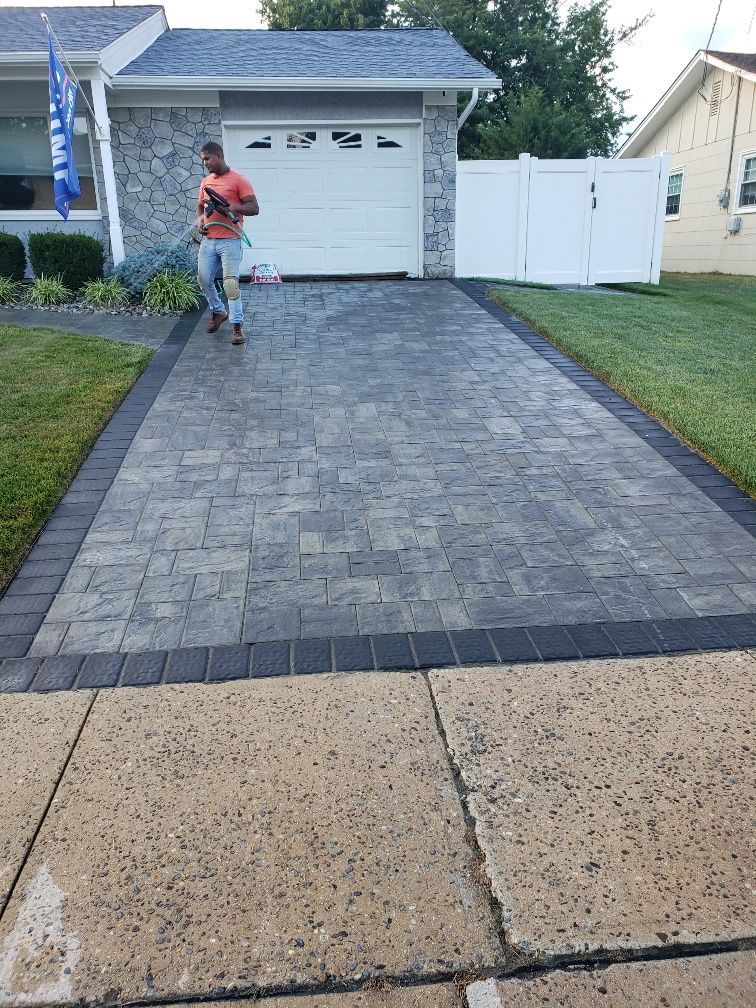 A man is walking down a brick driveway in front of a house.