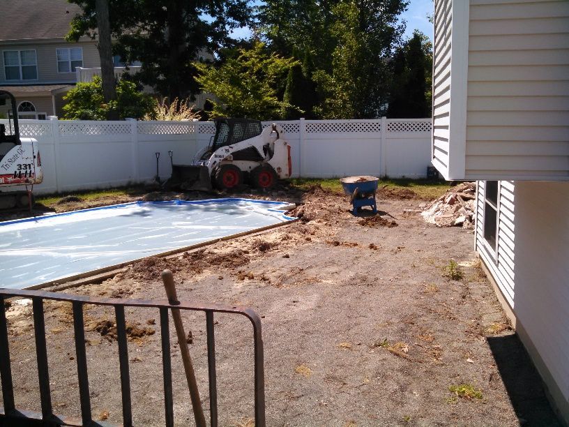 A bobcat is parked in the backyard of a house.