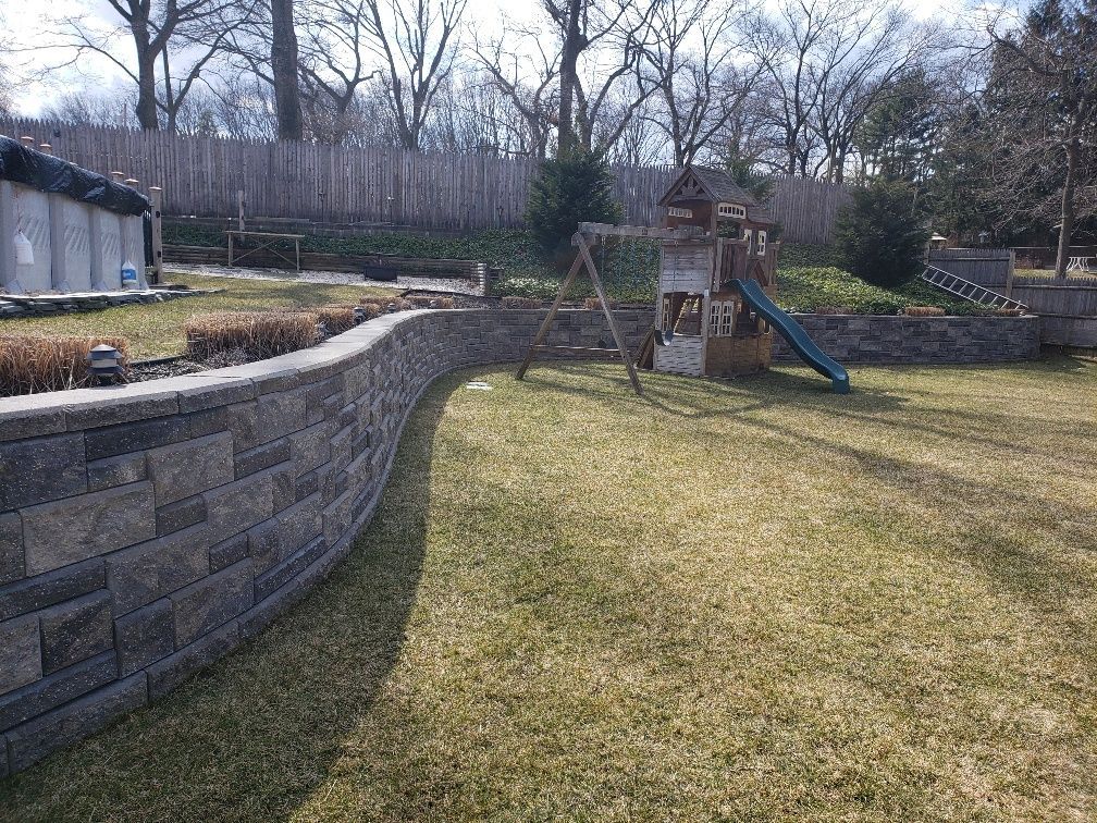 A backyard with a playground and a brick wall.