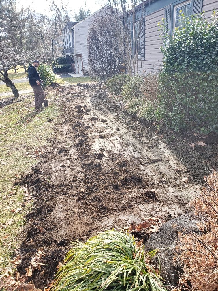 A man is standing next to a pile of dirt in front of a house.