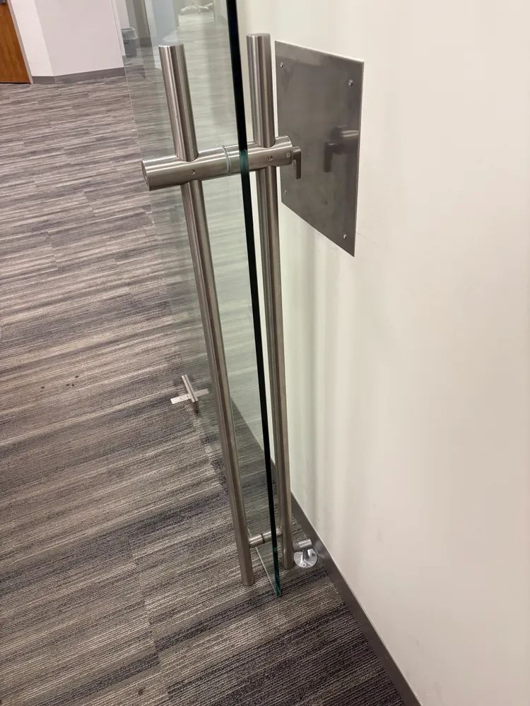 Glass office door with metal handle and gray carpeted floor