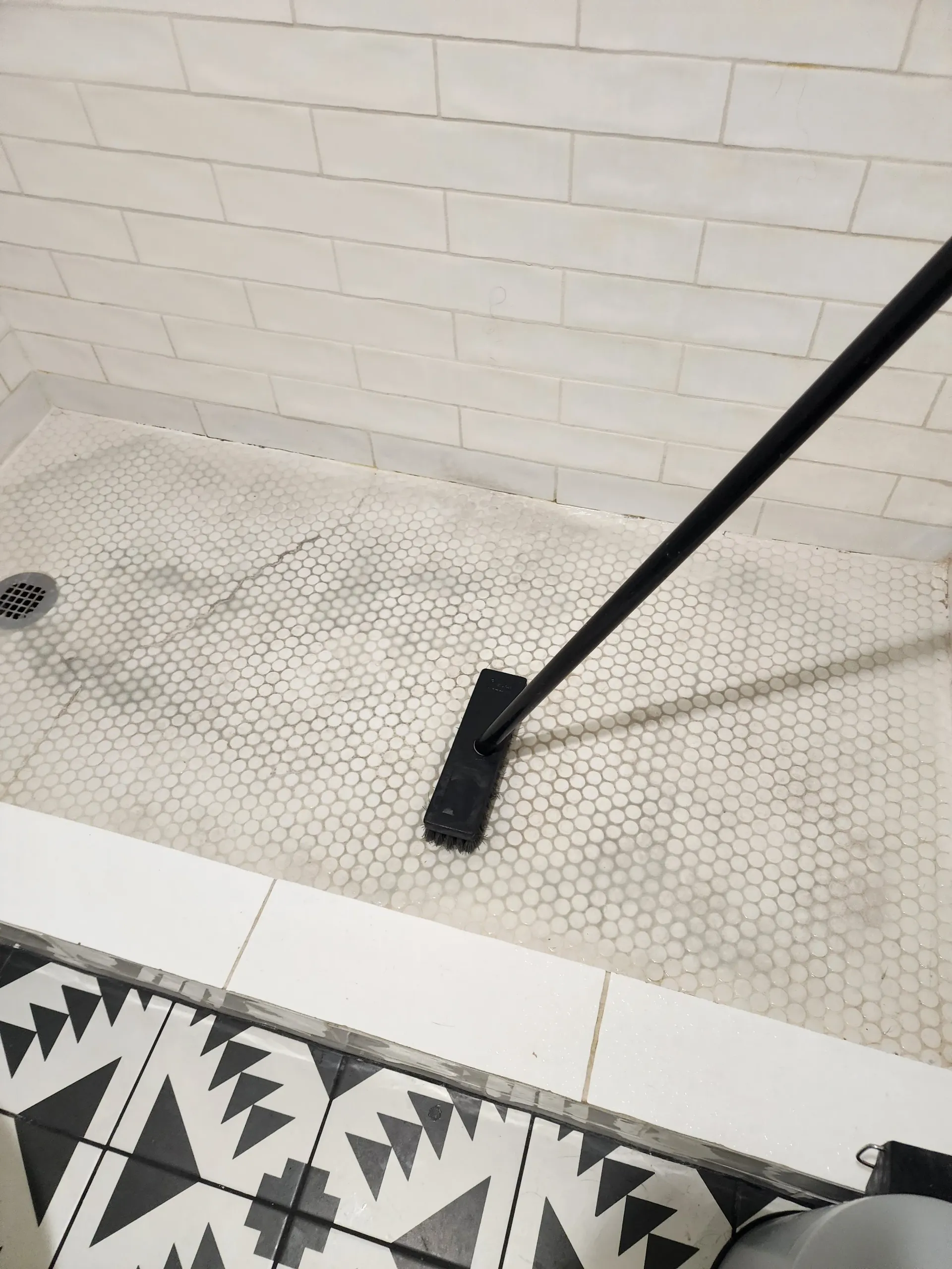 a person is cleaning a shower floor with a mop .