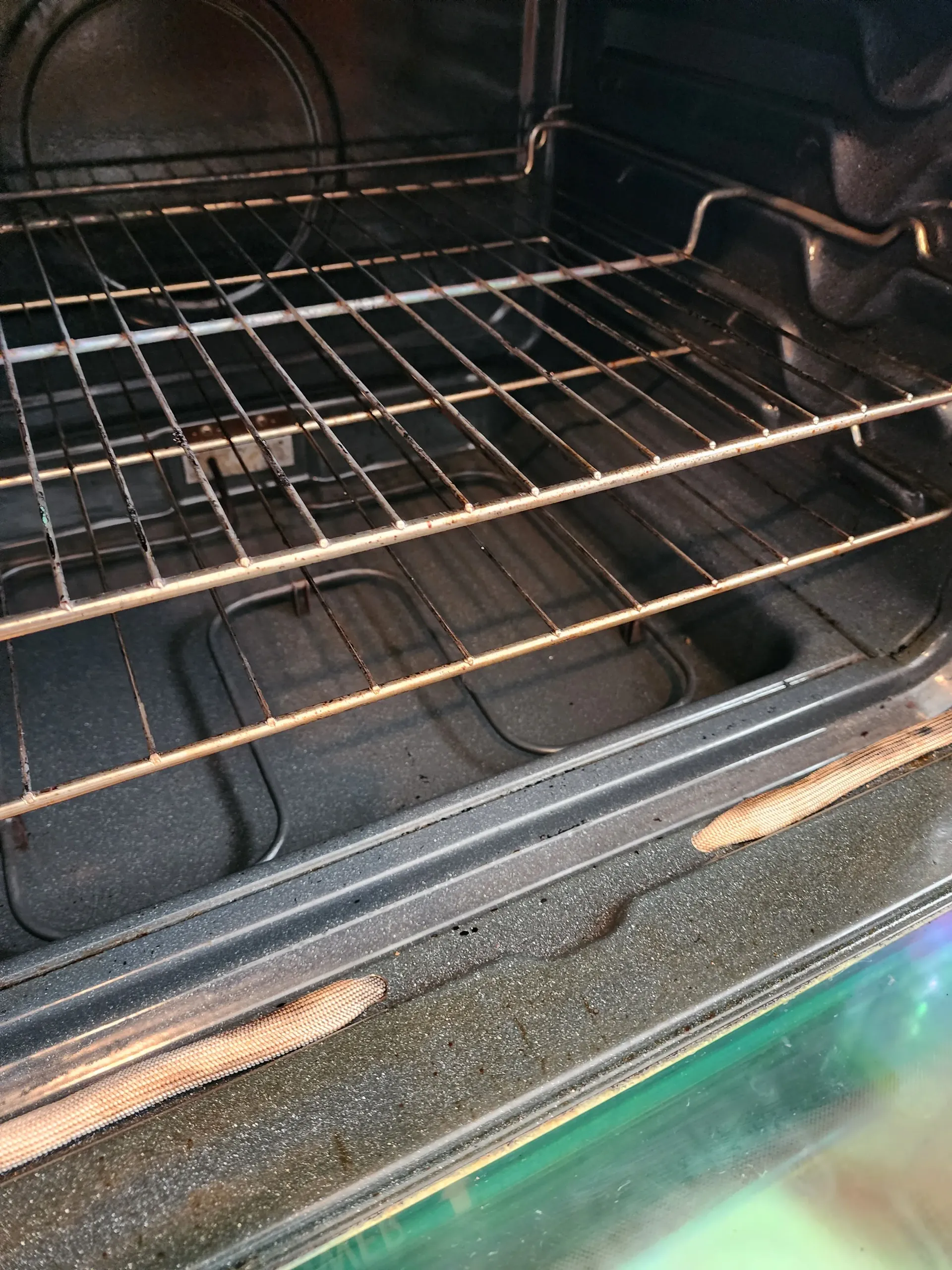 the inside of a dirty oven with a bunch of wire racks .