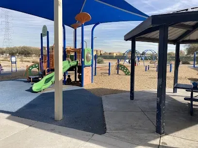A playground with a blue umbrella and a picnic table.