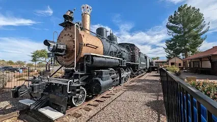An old train is parked on the tracks next to a fence.