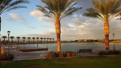 There are palm trees in the foreground and a lake in the background.
