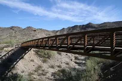 A bridge over a river in the desert with mountains in the background