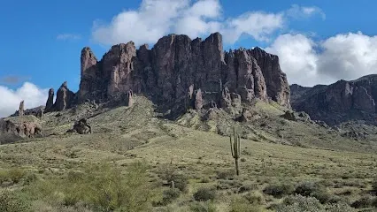 A desert landscape with a mountain in the background and a cactus in the foreground.