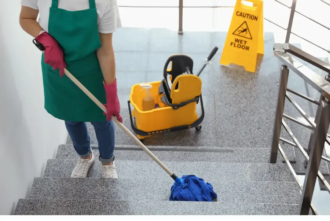 Two men are cleaning a building with a vacuum cleaner.