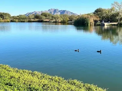 Two ducks are swimming in a lake with mountains in the background.