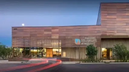 A large building with a lot of windows and a car driving past it.