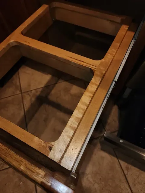 a stove top oven with a wooden drawer underneath it .